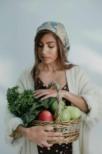 A woman holding a basketful of fruits and vegetables, symbolizing nourishing choices.