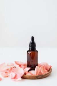 Jojoba oil in a glass bottle next to a few jojoba leaves